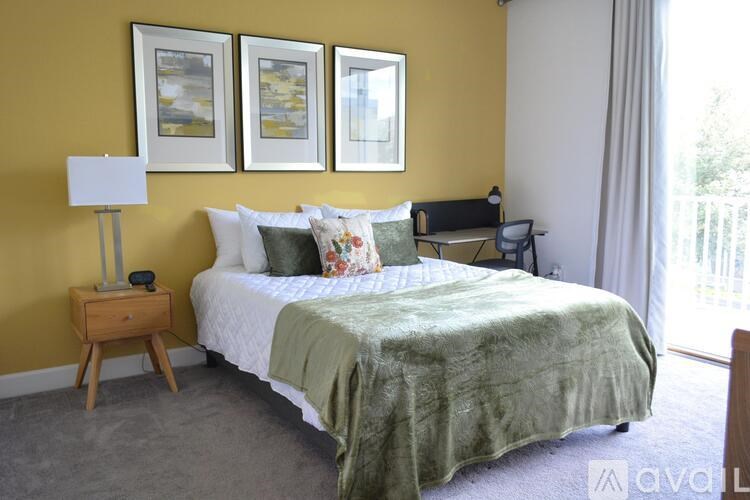 A bedroom with a bed, nightstand, and two pictures on the wall.