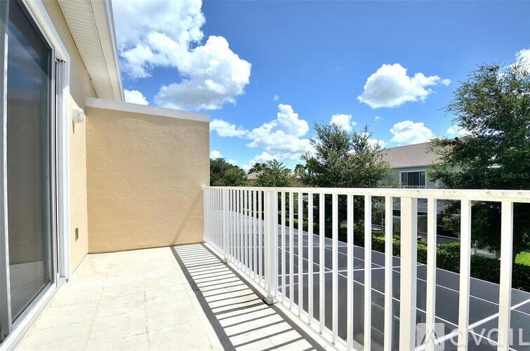 A balcony with a white railing and a beige wall.