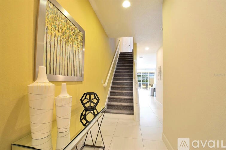 A hallway with a staircase and a decorative wall hanging.