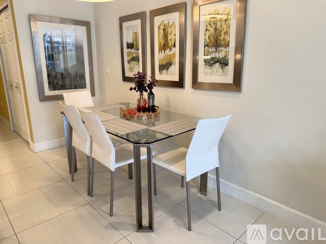 A glass dining table with four chairs and three framed pictures on the wall.