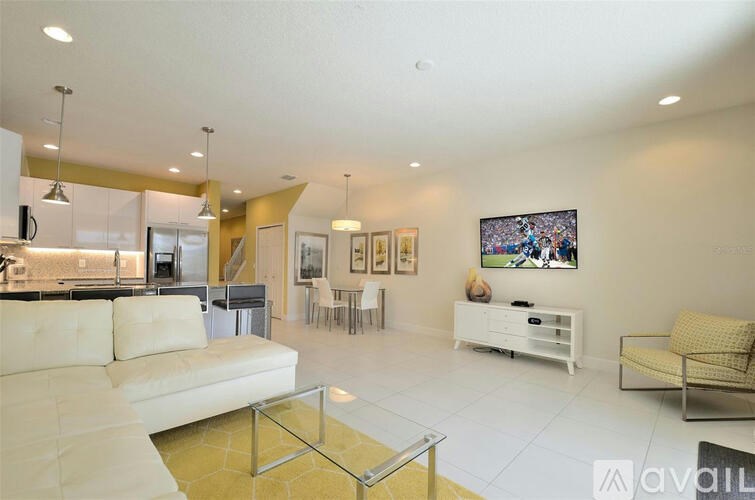 A spacious living room with a white sofa, a glass coffee table, and a large painting on the wall.