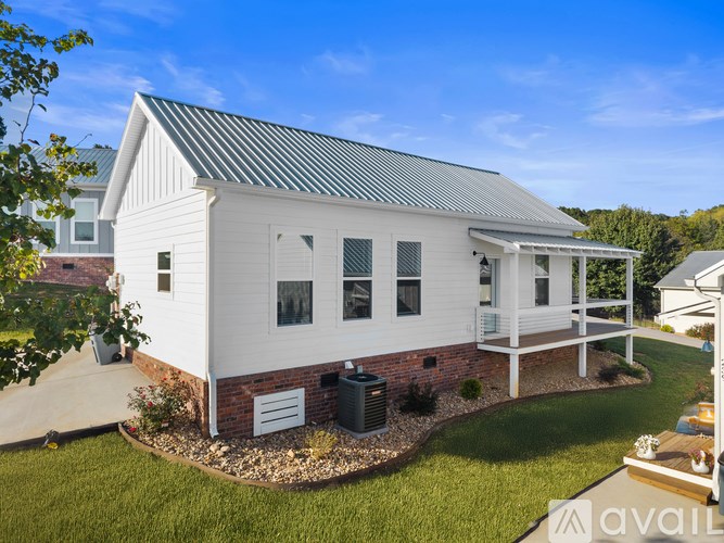 A white house with a grey roof and a small garden in front.