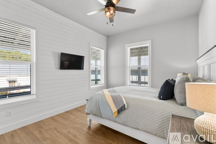 A bedroom with a bed, a ceiling fan, and a window with blinds.