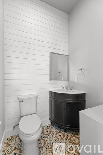 A white toilet sits in a bathroom with a black cabinet and a tiled floor.