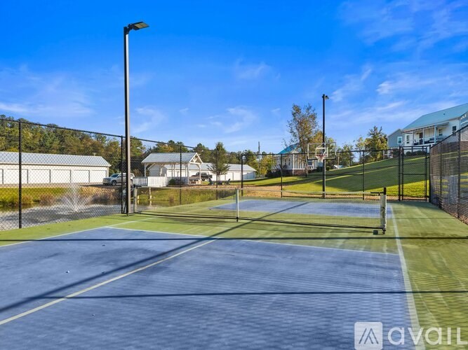 Tennis court with a blue surface and white lines, surrounded by a black fence.