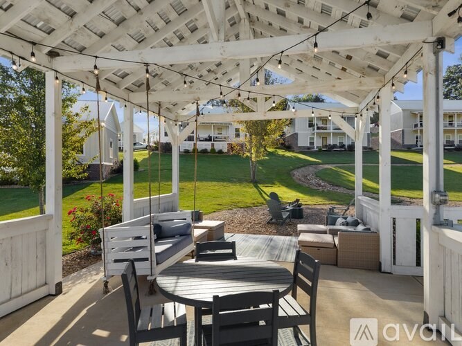 A patio with a table and chairs under a white pergola.