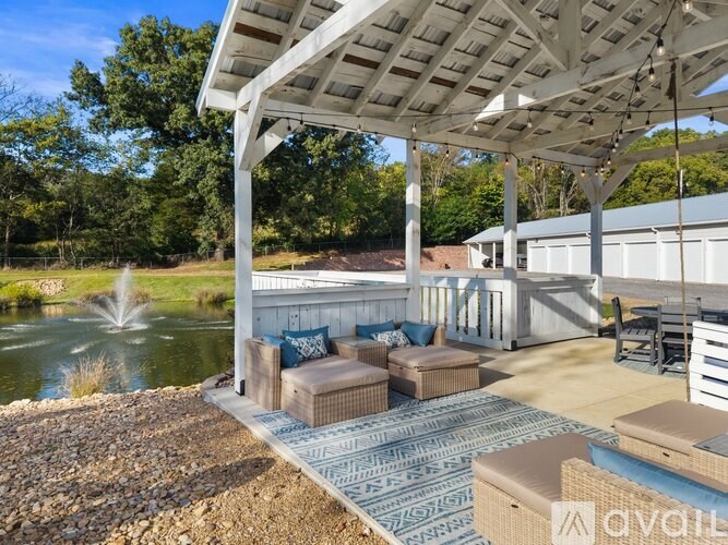 A patio area with a white pergola and a fountain in the background.