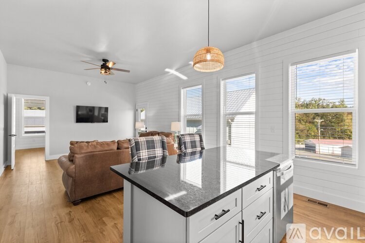 A modern kitchen with a brown sofa and a ceiling fan.