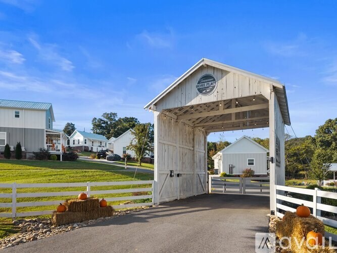 A white barn with a wooden gate and hay bales in front.