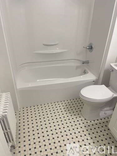 A white toilet sits next to a bathtub in a bathroom with black and white tiles.