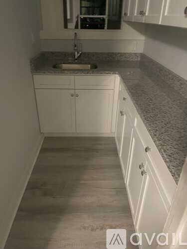 A kitchen with white cabinets and a granite countertop.