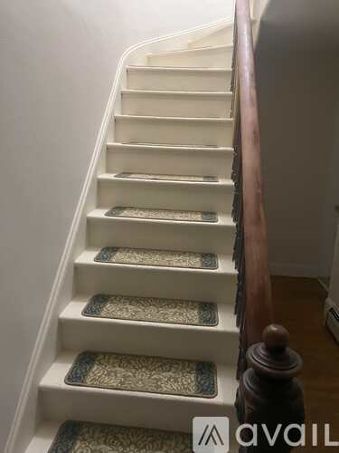 A staircase with a wooden handrail and decorative tiles on the steps.