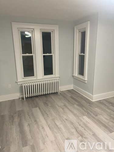 A room with a white radiator and wooden flooring.