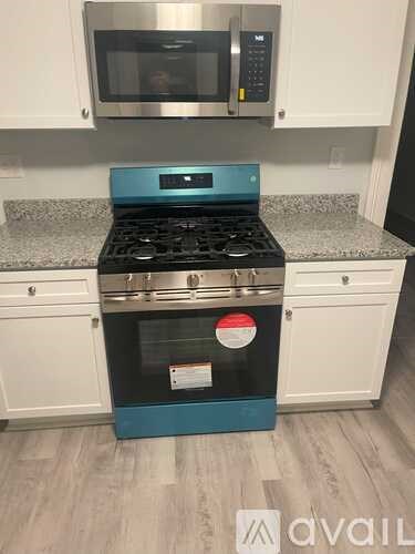 A blue stove top oven with a stainless steel microwave above it.