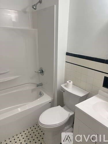 A white toilet sits next to a white bathtub in a bathroom.