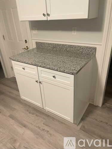 A kitchen island with a granite countertop and white cabinets.