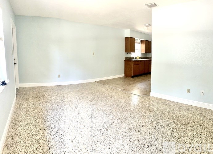 A spacious room with a kitchenette in the background.