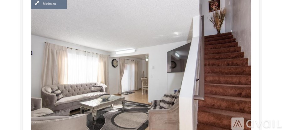 A living room with a couch, a coffee table, and a staircase.