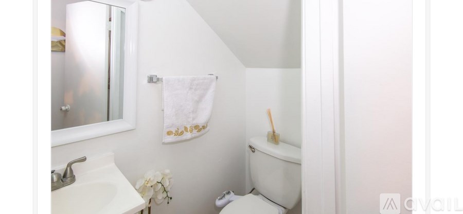 A white bathroom with a towel hanging on the wall.