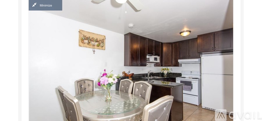 A modern kitchen with white appliances and a glass dining table.