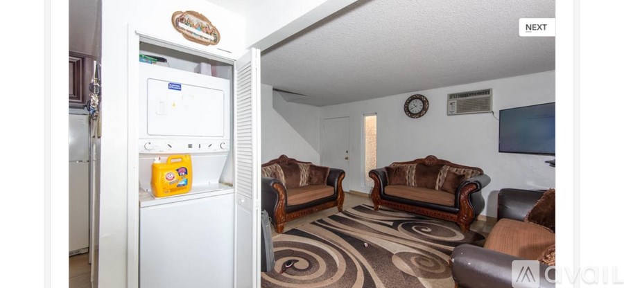 A living room with a white fridge and a TV on the wall.