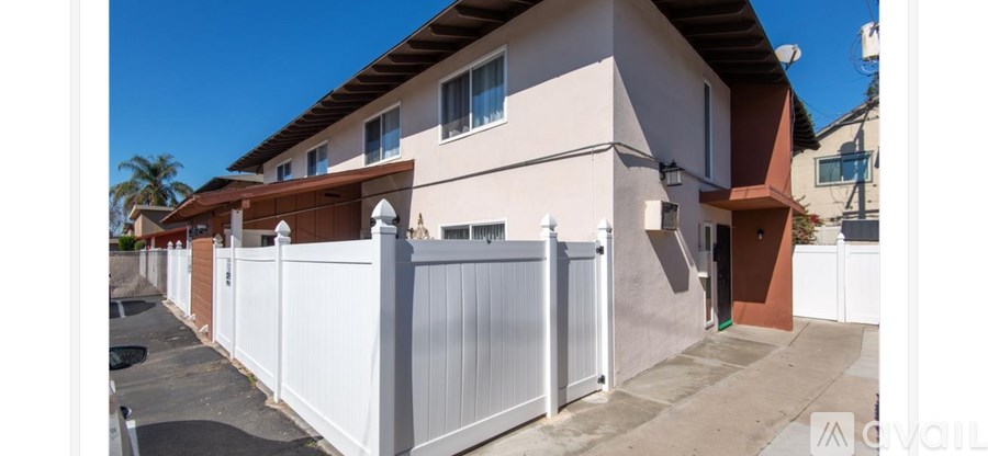 A white fence in front of a two-story house.