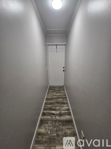 A hallway with a door at the end and a wooden floor.