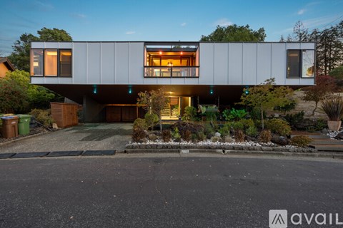 A modern house with a large front yard and a driveway.