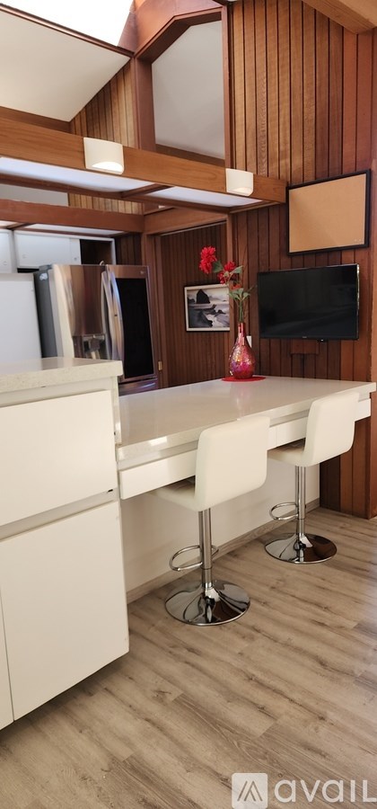 A kitchen with white chairs and wooden walls.
