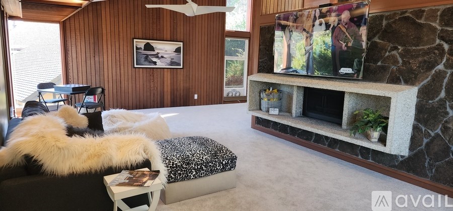 A living room with a stone fireplace and a flat screen TV mounted above it.