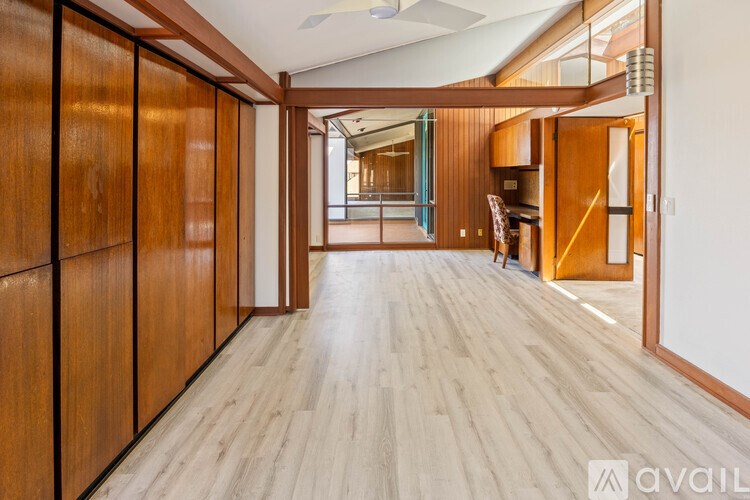 A hallway with wooden floors and walls leading to a kitchen area.