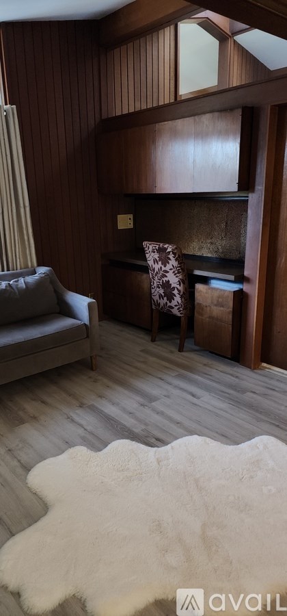 A room with wooden walls and a grey couch.