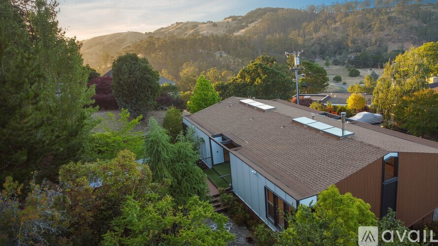 A house with a brown roof is surrounded by trees and is available for purchase.