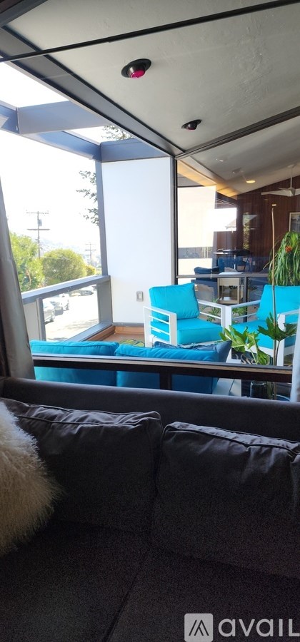 A living room with a grey couch and a white fluffy pillow.