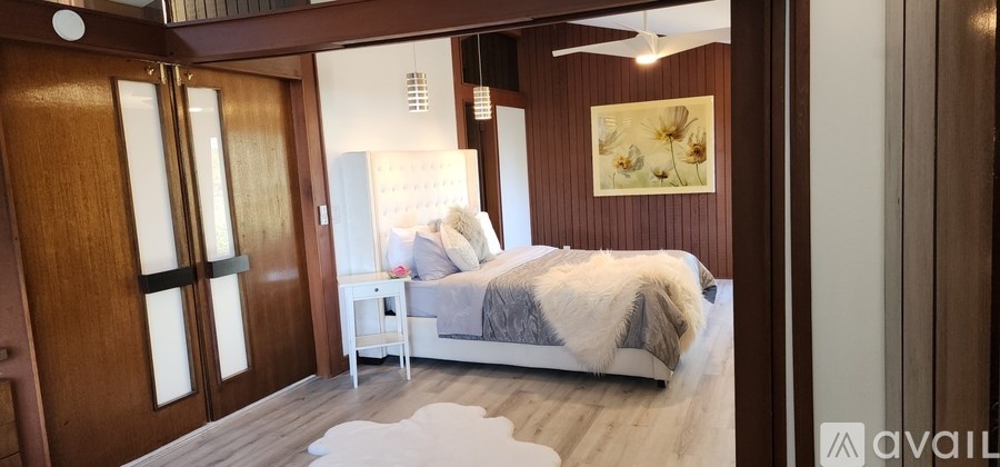 A bedroom with a bed, nightstand, and a painting on the wall.