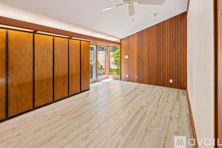 A room with wooden walls and floor and a ceiling fan.