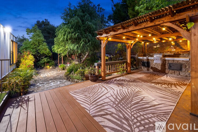 A wooden deck with a gazebo and a stone fireplace.