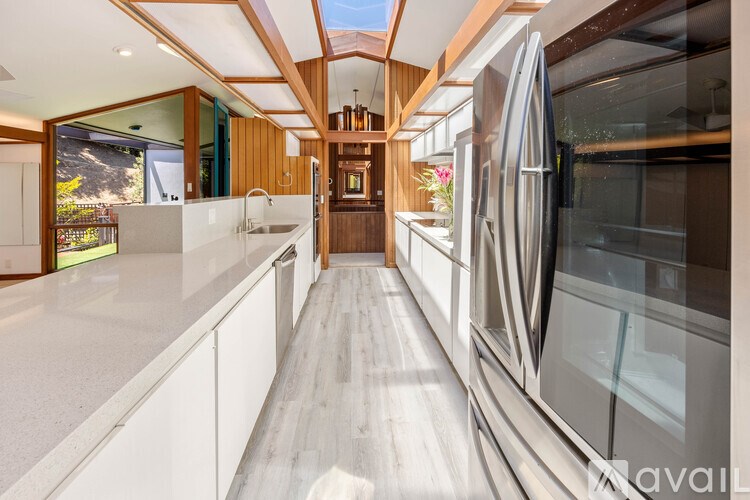 A modern kitchen with a long counter and a refrigerator on the right.