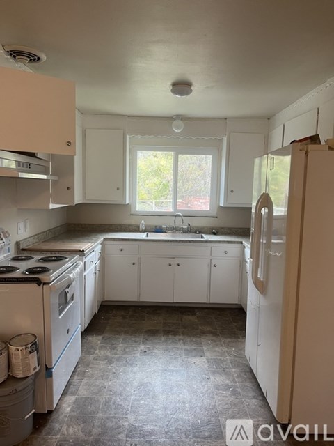 A kitchen with white cabinets and a window.