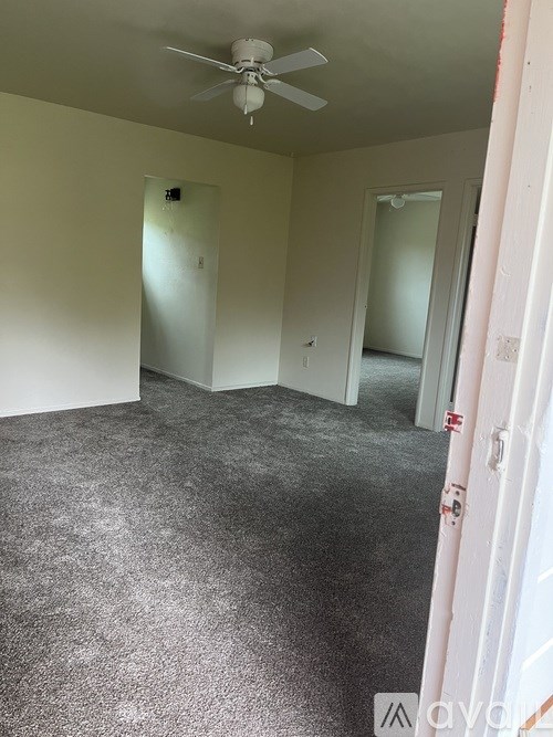A room with a ceiling fan and carpeted floor.