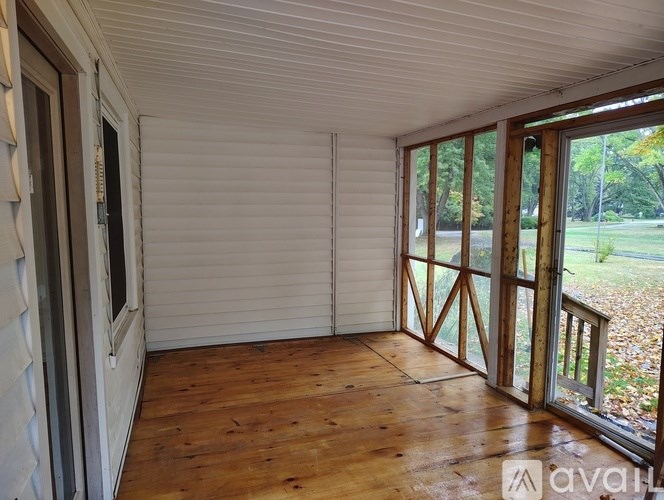 A room with wooden floors and a sliding door leading to a backyard.