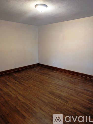 A room with wooden flooring and a white wall.