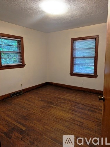 A room with wooden floors and two windows.