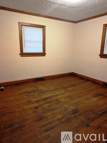 A room with wooden floors and two windows.