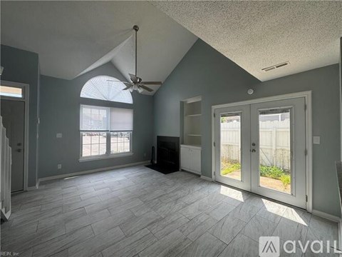 A spacious room with a ceiling fan and a large window.