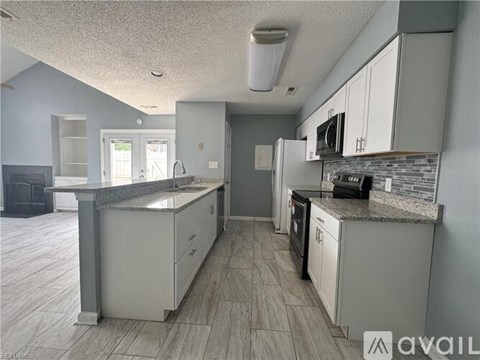 A kitchen with white cabinets and a granite countertop.
