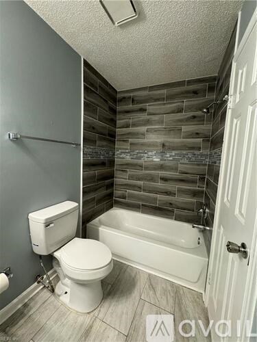 A white toilet sits next to a white bathtub in a bathroom.