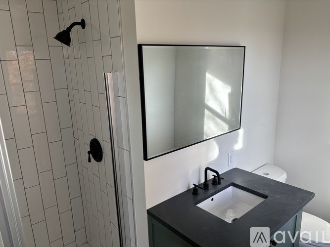 A bathroom with a black countertop and a glass shower door.
