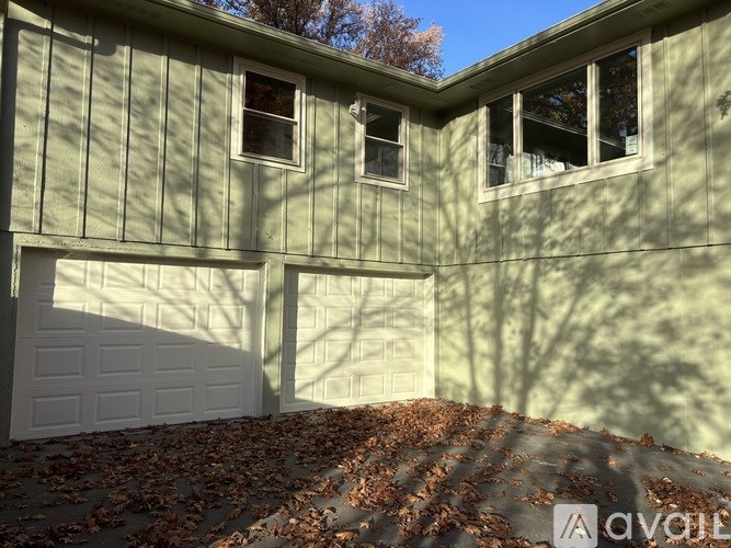 A house with a white garage door and a tree shadow on the wall.