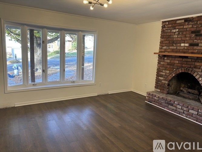 A room with a fireplace and a window overlooking a street.